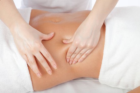 Beautiful girl having stomach massage. Body care concept in studio